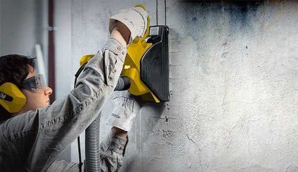 A worker punches grooves in a wall