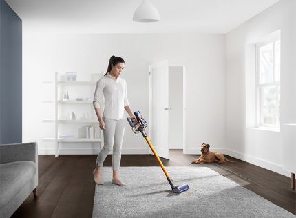 Une fille passe l'aspirateur avec un appareil Dyson