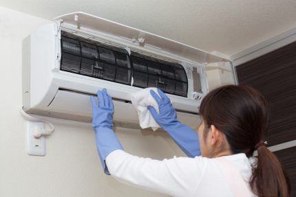 Woman cleaning wall-mounted split system