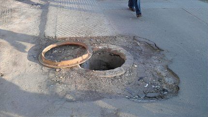 Puits d'égout à ciel ouvert sur la route