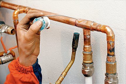 A master solders a copper pipe with solder