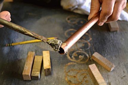 A craftsman coats a copper pipe with flux