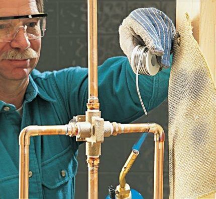 A craftsman is soldering a copper pipe