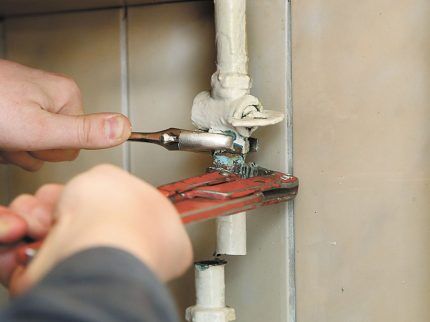 A mechanic unscrews a gas pipe