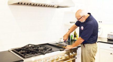 A specialist repairs a gas stove