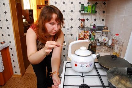 Une femme allume un brûleur avec une allumette