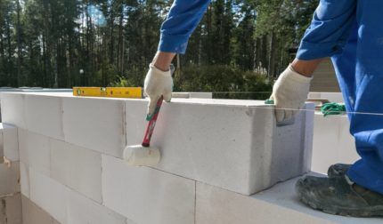 A builder levels a gas block with a hammer