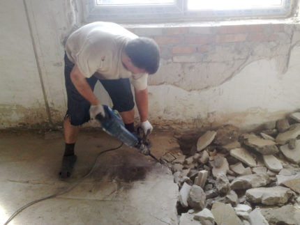 A man dismantles a floor screed with a hammer drill