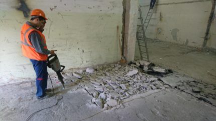 A man breaks a floor screed with a hammer drill