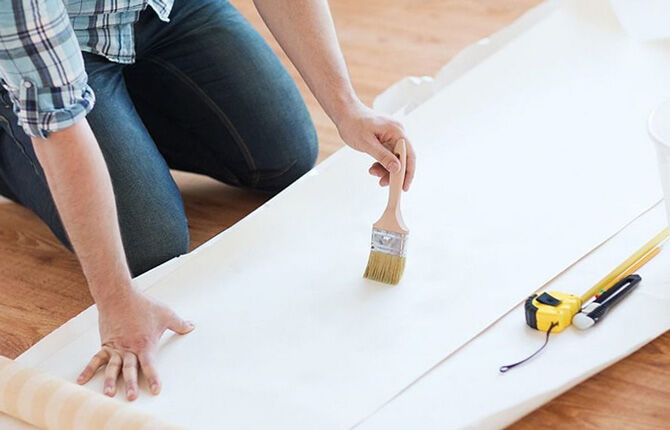 Applying glue to wallpaper with a paint brush